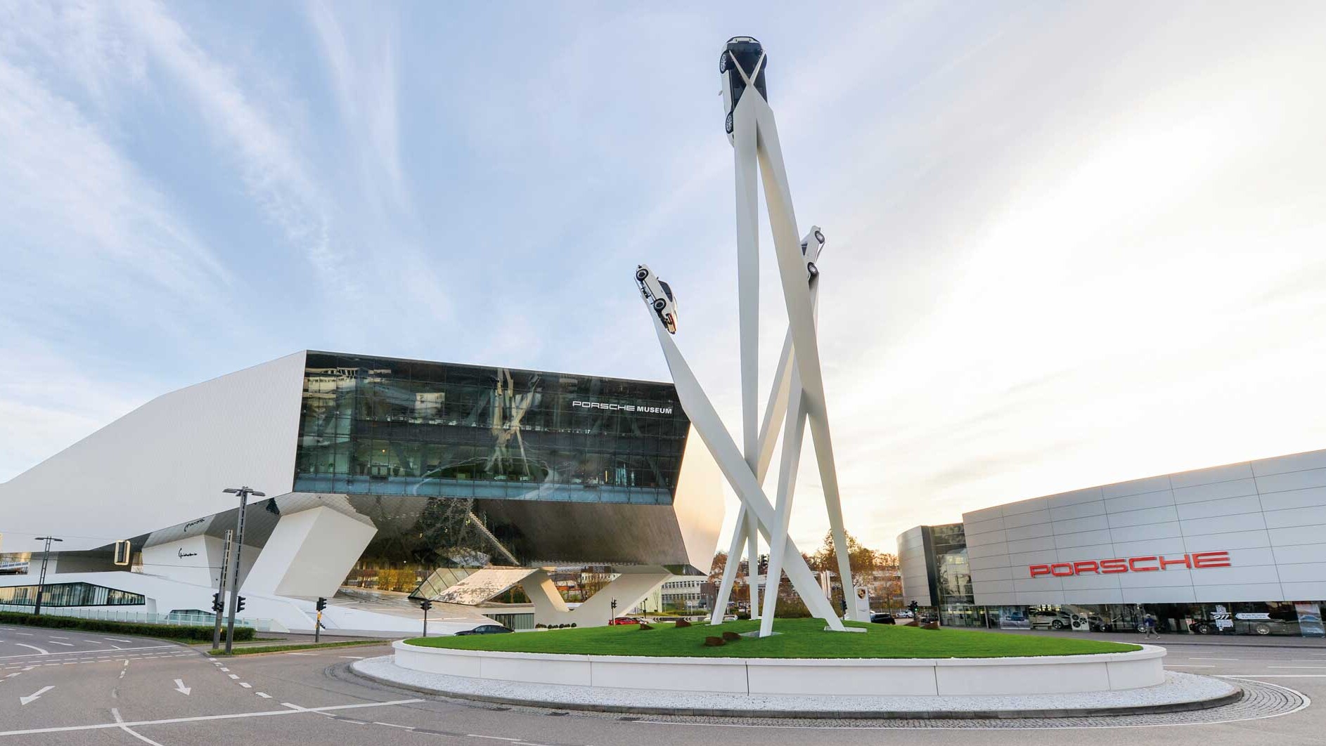 Blick auf das Porsche Museum und das Kunstwerk „Inspiration 911“ auf dem Kreisverkehr. Die drei Stelen tragen an ihren Spitzen in bis zu 24 Metern Höhe je einen Porsche 911.