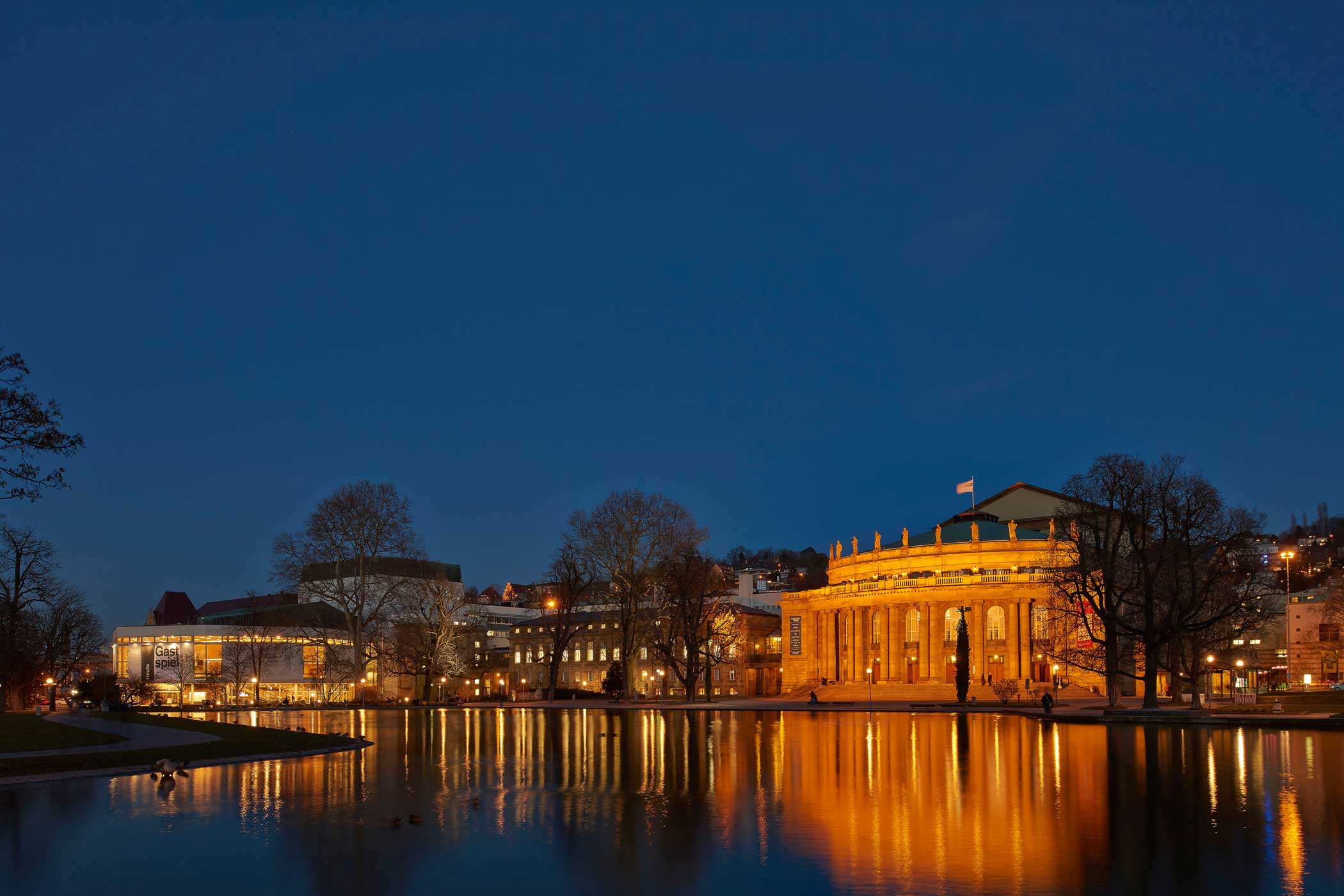 Aufnahme des Opernhaus bei Nacht. Weiter hinten links im Bild befindet sich das Schauspielhaus. Im Eckensee spiegeln sich die Lichter beider Gebäude.