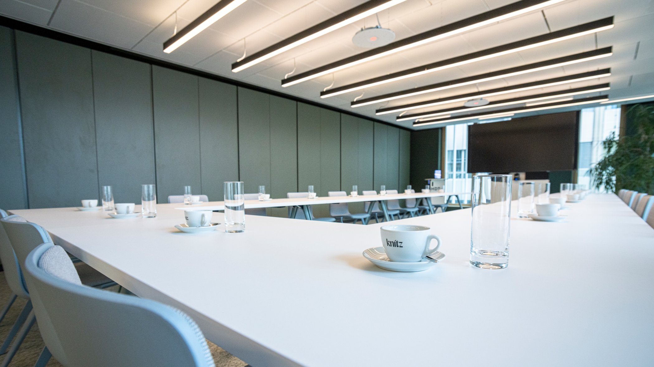 Weiße Tische in U-Form, auf den Tischen Tassen mit Logo der In-house-Gastro sowie Wassergläser.