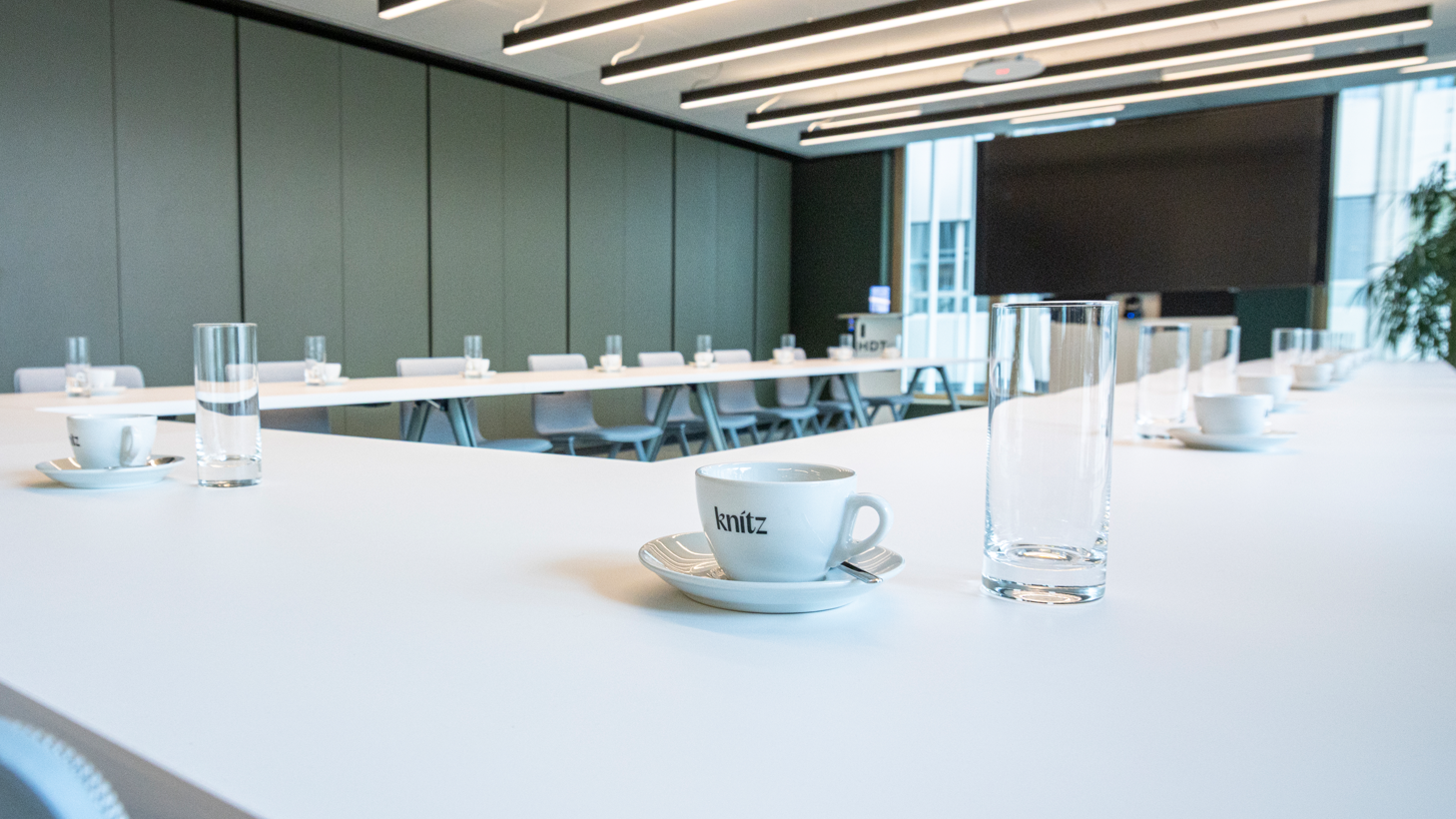 Weiße Tische in U-Form, auf den Tischen Tassen mit Logo der In-house-Gastro sowie Wassergläser.