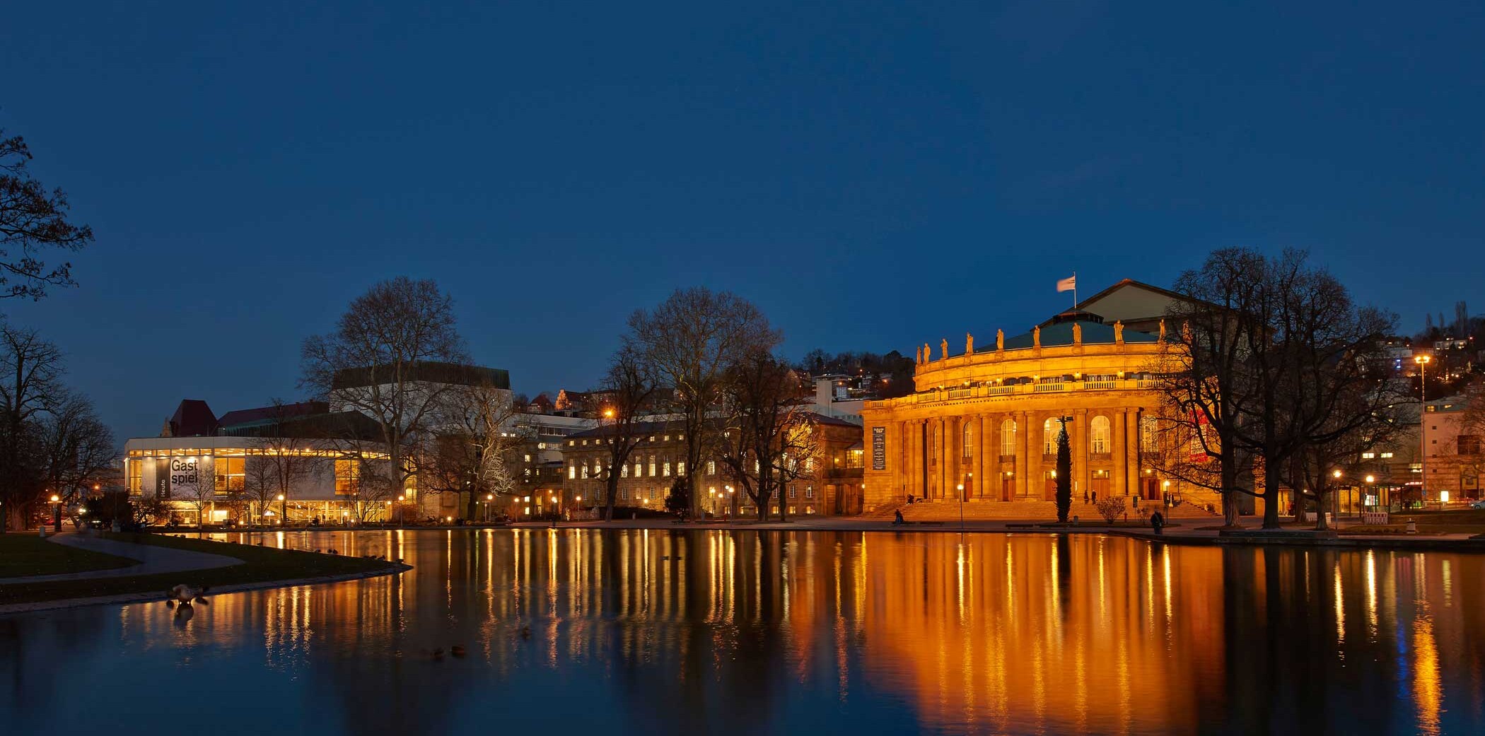 Aufnahme des Opernhaus bei Nacht. Weiter hinten links im Bild befindet sich das Schauspielhaus. Im Eckensee spiegeln sich die Lichter beider Gebäude.