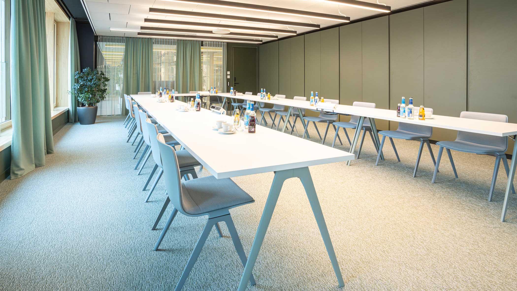 Klassischer Konferenzraum in gedeckten Farben mit Tischen in U-Form.